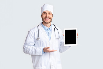 Friendly doctor showing digital tablet with blank screen