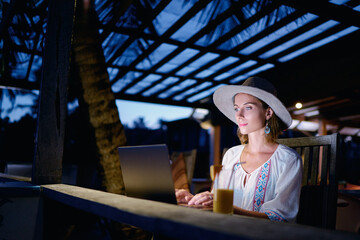 Obraz na płótnie Canvas Work and travel. Study and vacation. Working outdoors. Freelance concept. Pretty young woman using laptop in tropical beach bar cafe.