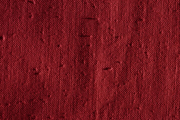 Texture of a dark red linen fabric with many defects. Old uneven textile material for background....