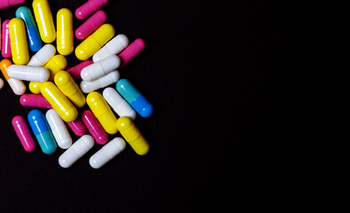 A scattering of multi-colored pills on a dark background close-up. Medical concept