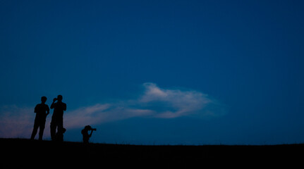 Silhouette crowd people stand in the dark night and see into the sky