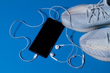 Sneakers, phone and headphones on a blue background close-up