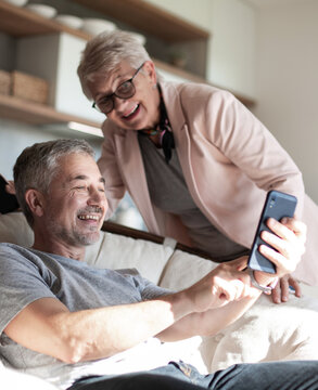 cute elderly couple looking at photos on their smartphone .