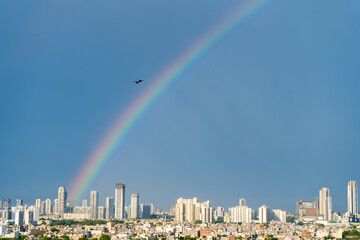 Aerial cityscape shot of buildings in gurgaon delhi noida with a rainbow behind them on a monsoon...