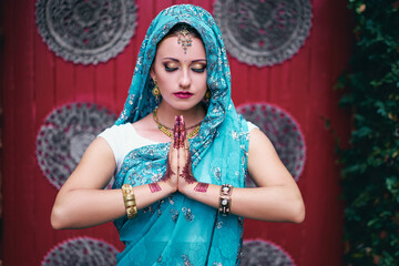 Beautiful young caucasian woman in traditional indian clothing sari with bridal makeup and jewelry and henna tattoo on hands.