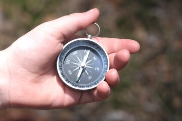 Old classic navigation compass in childs hand on natural background