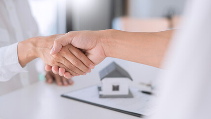 Fototapeta na wymiar Estate agent in suit sitting in an office desk shaking hands with customer after contract signature accept agreement finish buying or rental real estate for transfer right of property.