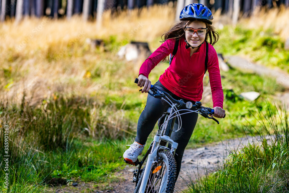 Wall mural Healthy lifestyle - teenage girl biking in forest
