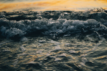 Sea white foam on the crest of a wave. Bubbling water. The wave runs ashore. Sea waves at dawn.