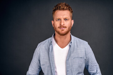 Fototapeta premium Headshot of handsome redhead male freelancer with appealing look, has red beard and mustache, looks directly at camera with serious look, wears white casual clothes. Facial expressions.