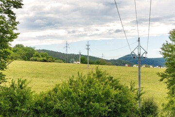 Obraz premium Power lines in the countryside against blue sky in summer day. The landscape of the Czech countryside. Energy distribution.