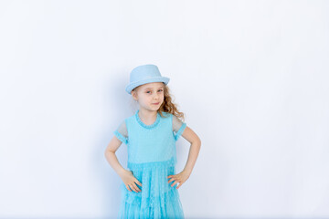 beautiful girl 6 years old in a blue dress with a hat on a white isolated background, space for text