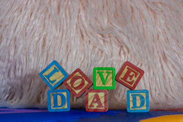 A fathers day message written out with children's wooden toy letter blocks on a play mat
