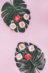 Japanese Food Sushi with Salmon and Ginger on Tropical Leaves Monstera Pink Background Top View Copy Space Vertical