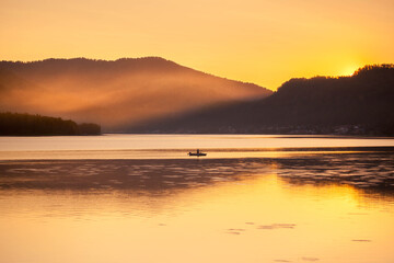Obraz premium sunset on the sea with a boat and mountains