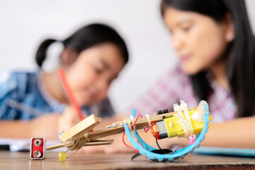 A teacher and an Asian female student build a motor vehicle in a science lesson