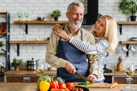Senior couple spending time together while cutting vegetables at kitchen