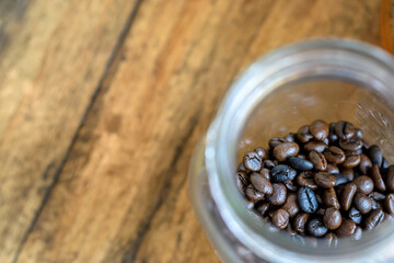 Close up of Roasted coffee beans in a glass jar on wooden table background. - 355906013