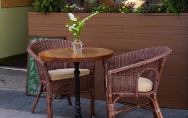 A table and chairs stand in the street near the cafe