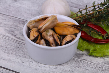 Pickled mussels in the bowl served pepper, garlic and salad