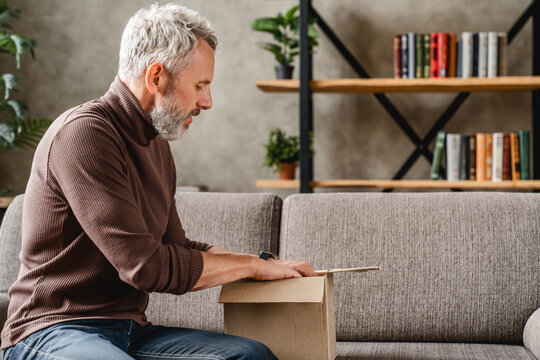 Middle aged man opening delivery box at home