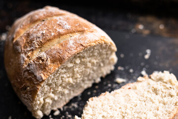 Detail of freshly baked homemade bread on black and wooden background, bakery setting.