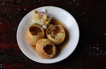 Panipuri or Golgappa Stuffed with Spicy Potato Paste and Tamarind Water in a Plate Isolated on Dark Background, Also Known as Phuchka, Paani Patashi, Gup Chup