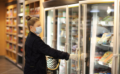 supermarket shopping, face mask and gloves,Woman choosing frozen food from a supermarket freezer