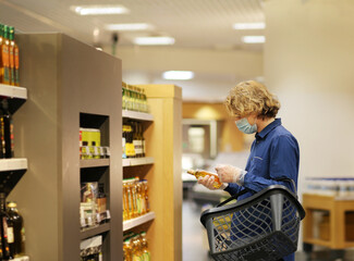 Supermarket shopping, face mask and gloves,Young man shopping in supermarket, reading product information