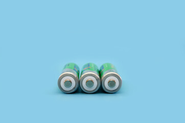 Three rechargeable batteries isolated on a blue background.