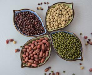 Collection set of beans, legumes on ceramic bowl on white wooden background