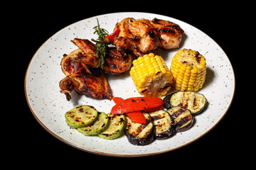 Grilled chicken wings with vegetables on a black background