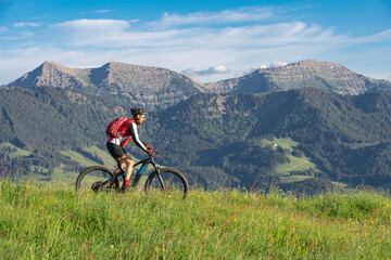 pretty senior woman riding her electric mountain bike on the mountains above Oberstaufen, Allgau...