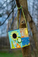Birdhouse hangs on a tree. Funny and colorful colors.