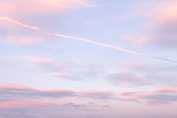 Fototapeta na wymiar Warm purple sky and clouds at sunset with vapour trails (chemtrails)