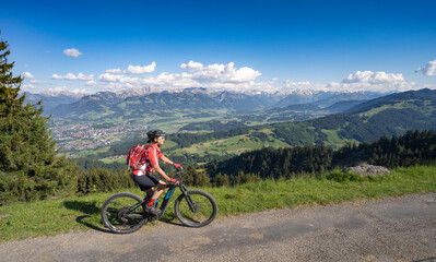 Fototapeta na wymiar pretty senior woman riding her electric mountain bike on the mountains above the Iller valley between Sonthofen and Oberstdorf, Allgau Alps, Bavaria Germany 