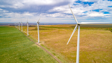 Fototapeta na wymiar Row of rind turbines high on a ridge catching the wind