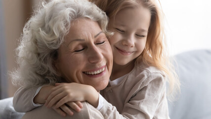 Close up of cute little preschooler granddaughter hug cuddle show love and gratitude to senior...