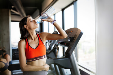 Fototapeta na wymiar Refreshing after workout. Beautiful young woman drinking water to stay hydrate