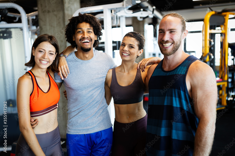 Wall mural beautiful fit people working out in gym together