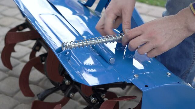 attach the spring to the cultivator,farmer install a spring on the casing for the cultivator of the motoblock