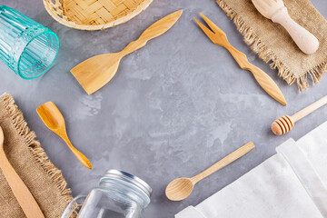 Zero waste concept. Eco bag, glass and wooden cutlery on a gray background. Eco friendly wooden cutlery, sackcloth and mason jar. Plastic free concept. Top view. Copy space
