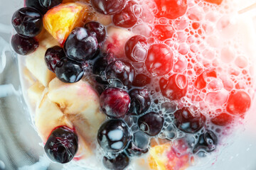 Fototapeta na wymiar Healthy food concept. making a smoothie with fruits and berries. blended in slow motion from above. selective focus