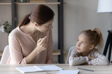 Strict young Caucasian mother studying with little schoolgirl daughter, scold lecture for bad...