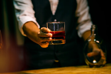 hand holding ice whisky glass, clinking glasses
