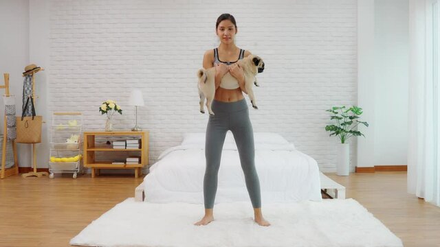 Asian woman workout squats excercise with dog at home