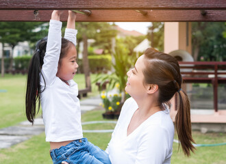 Portrait of Asian mother and daughter playing together in nature outdoors. Happy loving family having fun.