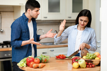 Young couple arguing in the modern kitchen at home - obrazy, fototapety, plakaty