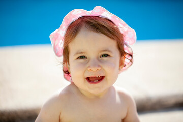 Bebé de quince meses sonriendo junto a la piscina