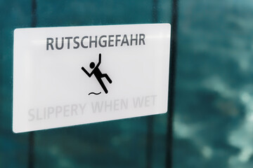 White slippery when wet sign with warning in German and English